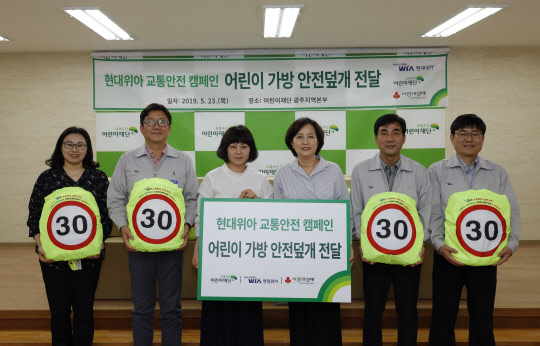 공경용 현대위아 모듈생산실장(왼쪽 두 번째)과 김은영 초록우산 어린이재단 광주지역본부장(왼쪽 네 번째) 등 현대위아의 어린이 가방 안전 덮개 전달식 참가자들이 기념촬영을 하고 있다. <현대위아 제공>